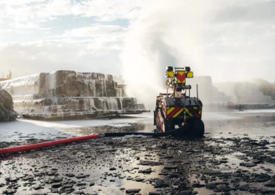 Colossus robot spraying foam during a firefighting mission in an industrial setting.